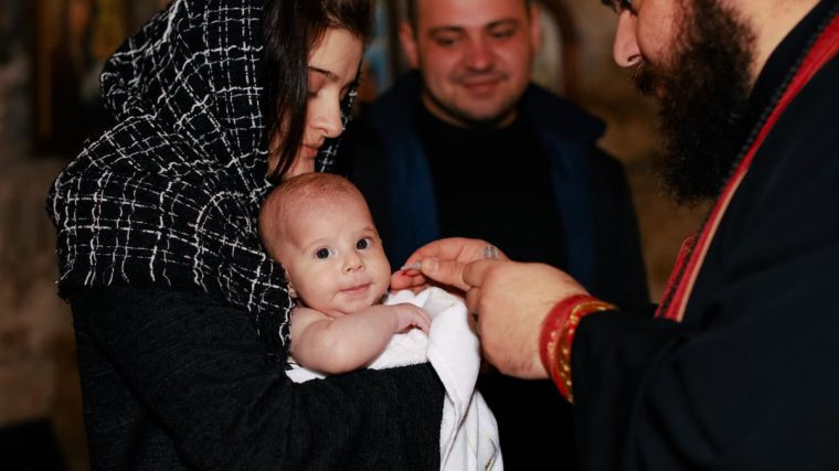 A traditional Orthodox baptism featuring a priest, baby, and family in an intimate ceremonial setting.