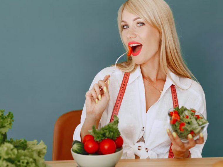 Woman enjoying a fresh salad with tomatoes and greens, promoting healthy eating.